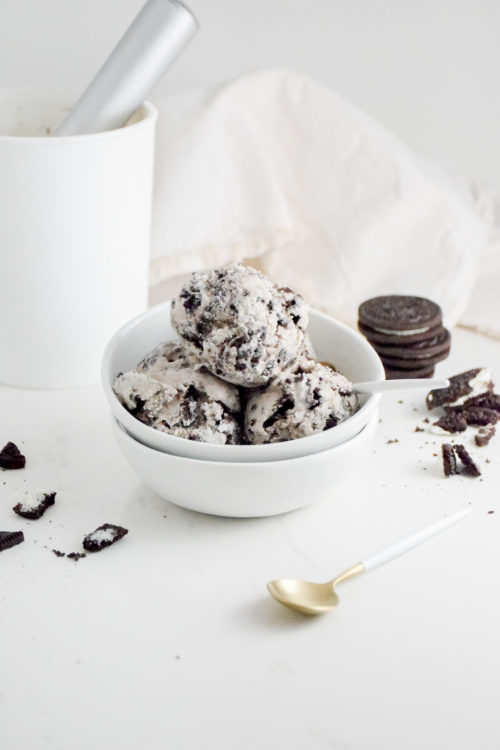 Cookies 'n Cream Ice Cream Scoops in a white bowl on a white background with crumbles cookies on either side