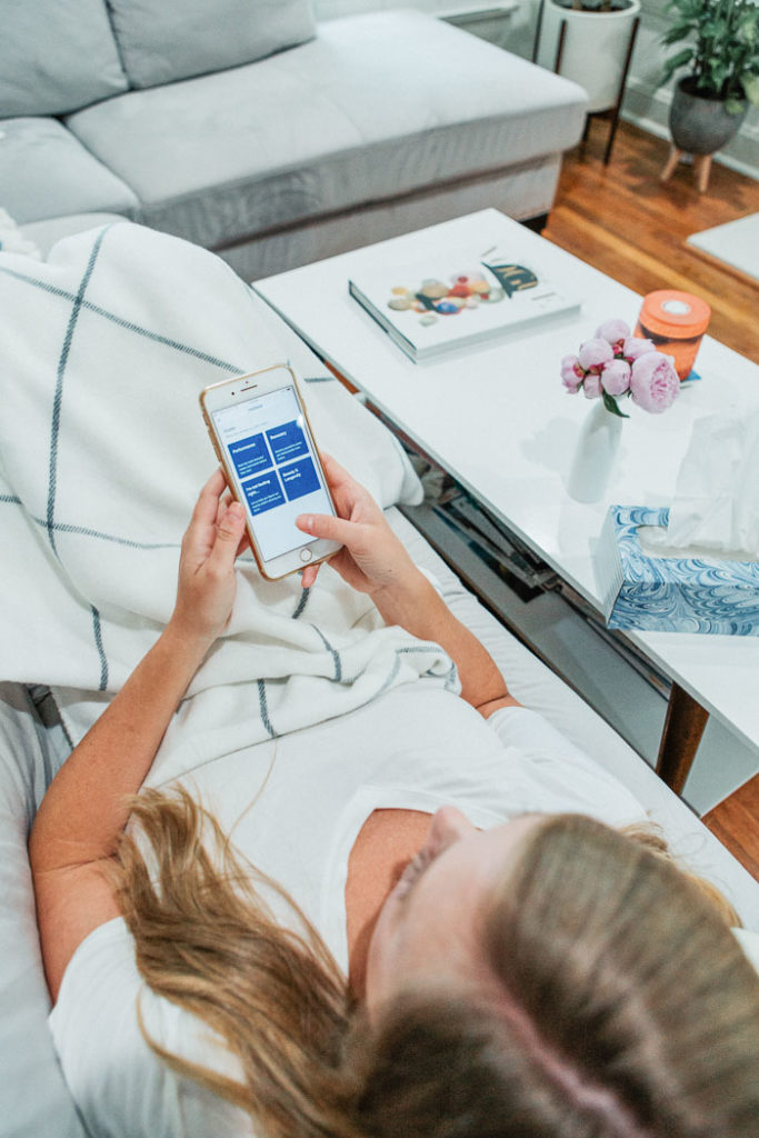 woman laying on couch looking at phone screen